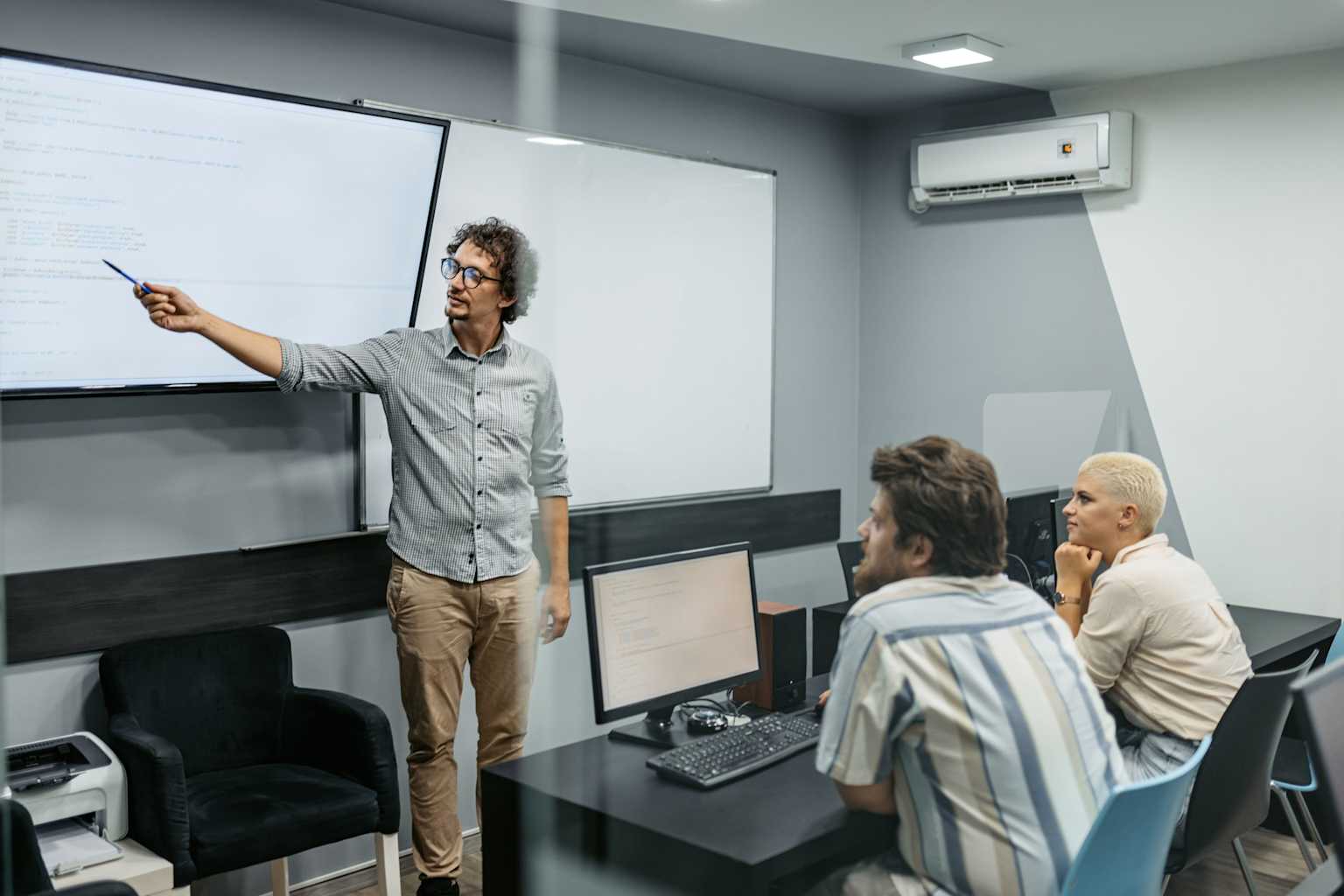 University professor teaching AI-related content to students using a digital screen and computers in a modern classroom